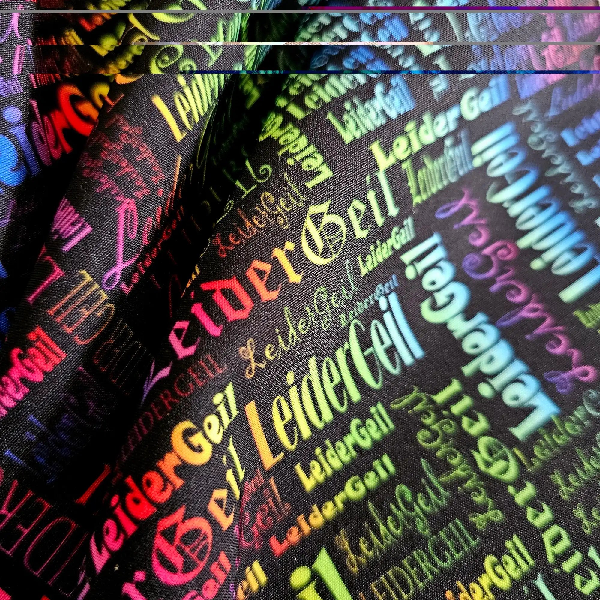 Schwarzer Stoff mit buntem, sich wiederholendem »LeiderGeil«-Text in verschiedenen Schriftarten.